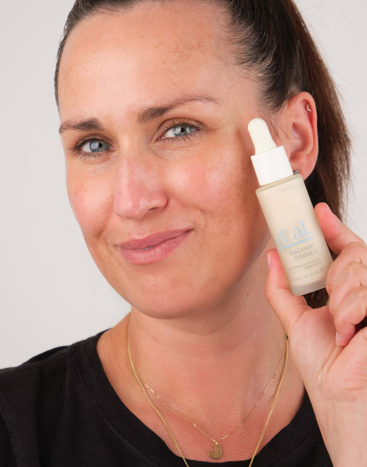 Woman holding et al. Radiant Primer bottle