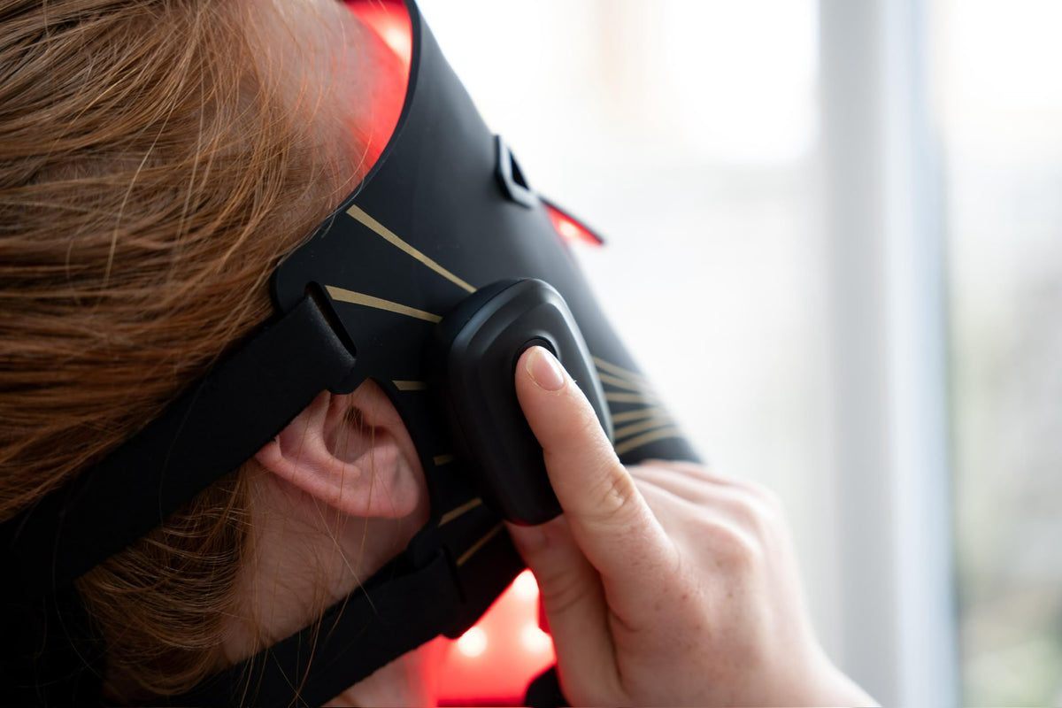 Woman using the SkinVitál LED Light Therapy Mask control button